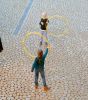 Zwei Kinder spielen mit Hula-Hoop-Reifen auf einem gepflasterten Hof.